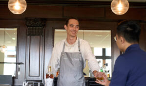 bartender handing a man a drink and smiling
