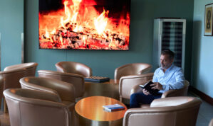 executive sitting in a lounge chair reading a book in front of a digital fire on tv